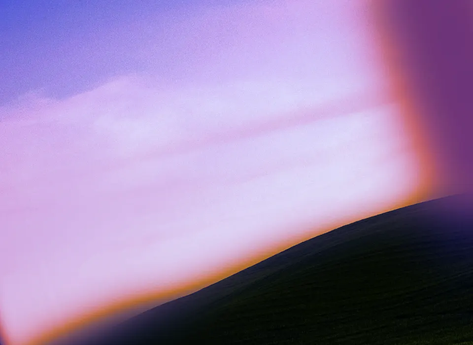 A dark hillside beneath a soft lilac sky edged with an orange glow.